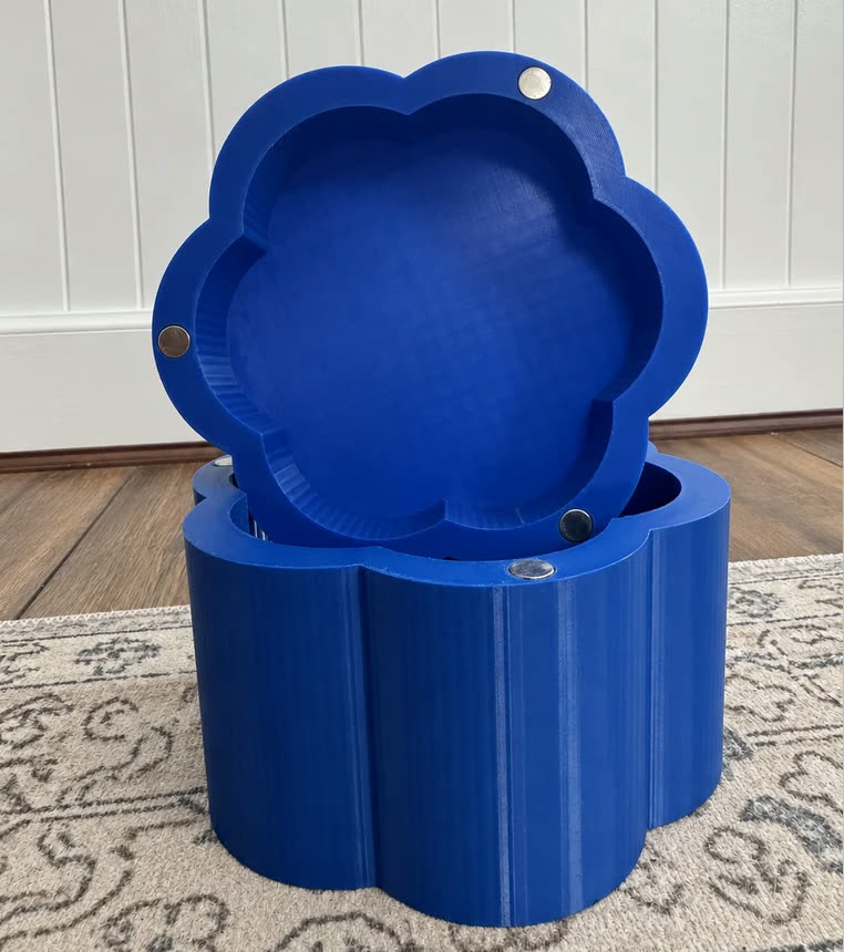 A blue six-petal magnetic box, lid resting open on the base